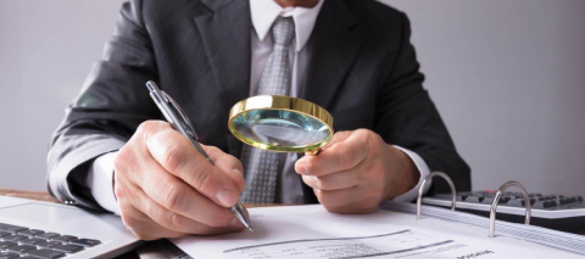 Man looking through books with magnifying glass