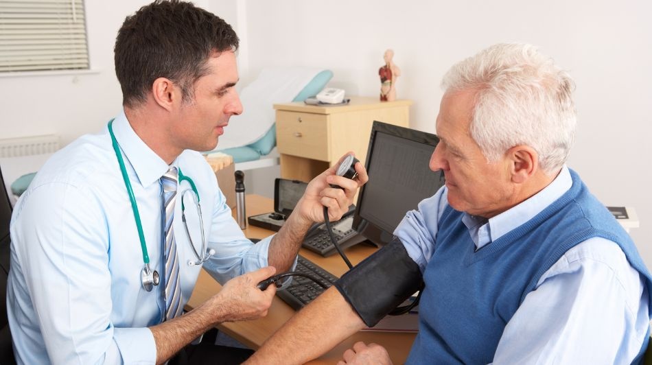 Healthcare professional measuring a patient's blood pressure during a consultation in a medical examination room.