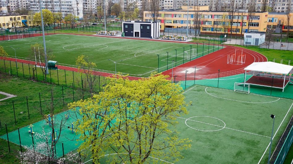 Modern school sports complex with football pitches, running track, and outdoor athletic facilities