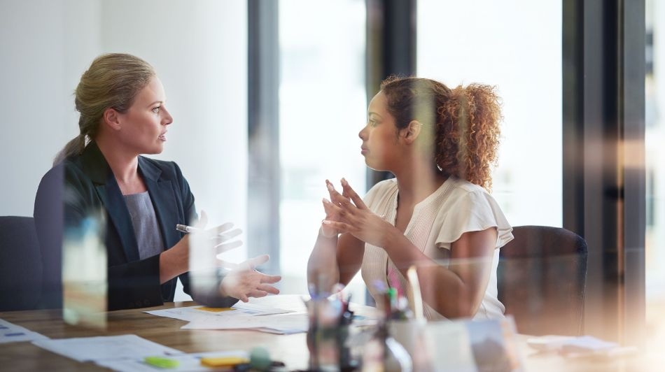 Business professionals in a meeting room discussing documents across a conference table.