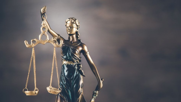 Classical justice statue holding balanced scales against a dark, cloudy background