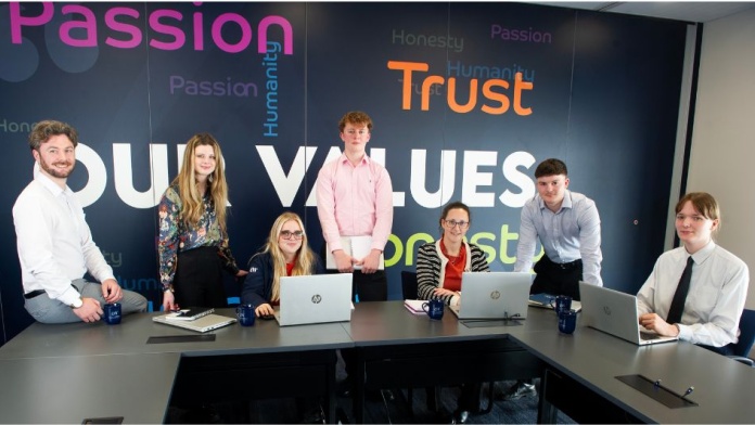 Tax Compliance Managers and apprentices at Armstrong Watson. Sitting at a desk with laptop