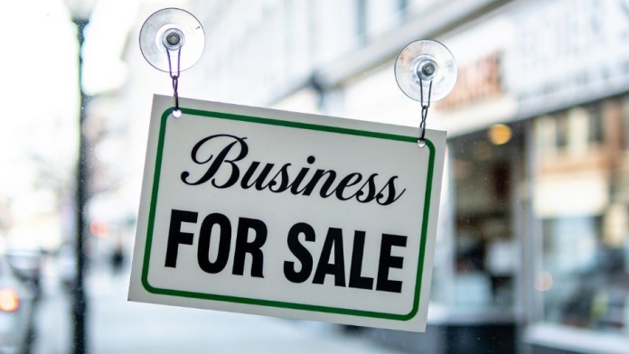Business for sale sign hanging in a shop window on a high street.