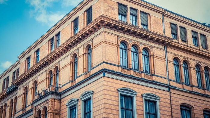 Historic sandstone office building with arched windows and detailed classical architecture.