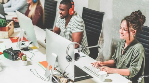 Office workers using desktop computers and headsets in a modern collaborative workspace