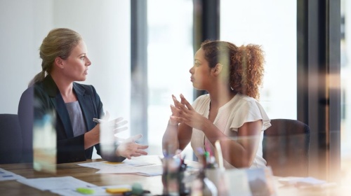 Business professionals in a meeting room discussing documents across a conference table.