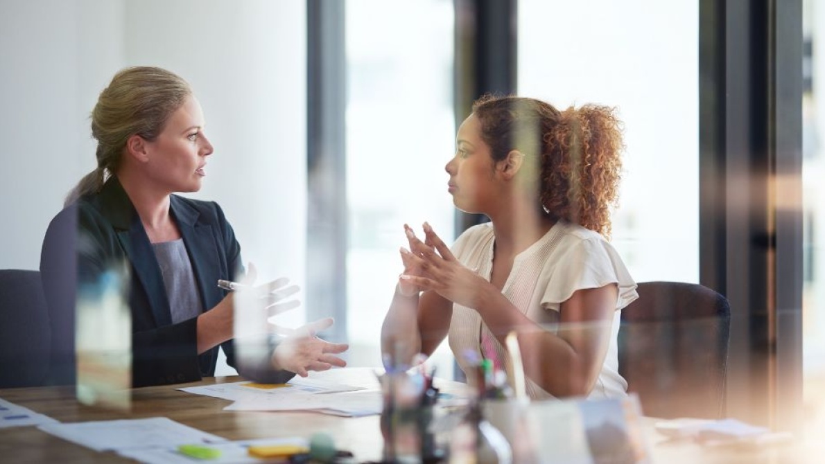 Business professionals in a meeting room discussing documents across a conference table.