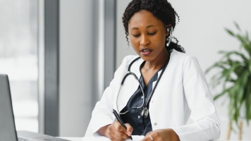 Female GP wearing stethoscope looking at patient notes