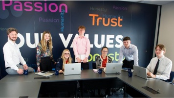 Tax Compliance Managers and apprentices at Armstrong Watson. Sitting at a desk with laptop