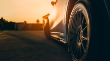 Close-up of a car wheel on a road at sunset with warm golden lighting.