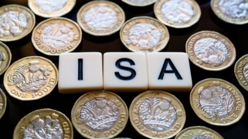 Wooden tiles spelling “ISA” surrounded by UK one‑pound coins, representing savings accounts.
