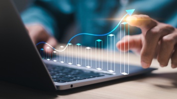 Hand interacting with a digital growth chart projected above a laptop, illustrating business performance, analytics, and financial growth.