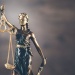 Classical justice statue holding balanced scales against a dark, cloudy background