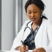Female GP wearing stethoscope looking at patient notes