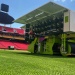 Grounds maintenance machine preparing stadium pitch on bright green football field.