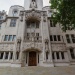 Ornate white stone Supreme Court building façade with arched entrance, carved figures, and tall windows.