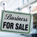 Business for sale sign hanging in a shop window on a high street.