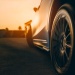 Close-up of a car wheel on a road at sunset with warm golden lighting.