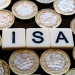 Wooden tiles spelling “ISA” surrounded by UK one‑pound coins, representing savings accounts.