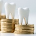 Three white tooth models displayed on stacks of gold coins, representing dental funding, costs, or investment in oral healthcare.