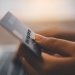 Close-up of a hand holding a payment card while making an online purchase on a laptop.