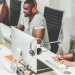 Office workers using desktop computers and headsets in a modern collaborative workspace