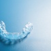 Clear dental aligner tray on a blue surface, used for discreet teeth straightening.
