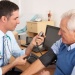Healthcare professional measuring a patient's blood pressure during a consultation in a medical examination room.